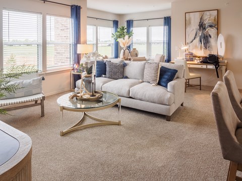 A living room with a white couch and a glass coffee table.