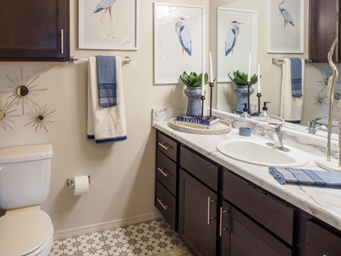 A bathroom with a toilet, sink, and mirror.