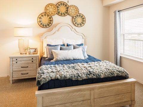 A bedroom with a bed, nightstand, and wall art.