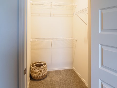 A small, empty room with a white door and a wicker basket on the floor.