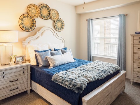 A bedroom with a bed, nightstand, and wall decor.