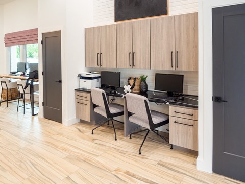 A kitchen with a desk and chairs.