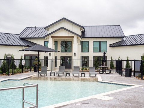 A black and white building with a pool in front.