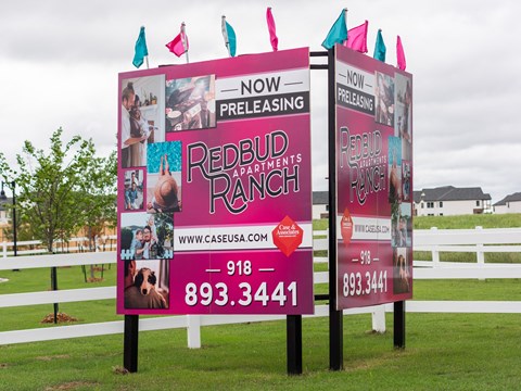 Two signs advertise the preleasing of Redbud Apartments.