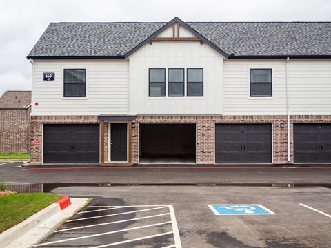 A white building with a black roof and a parking lot in front.