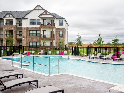 A pool area in front of a multi-story apartment building.