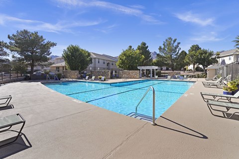 A swimming pool surrounded by a concrete patio and a metal railing.