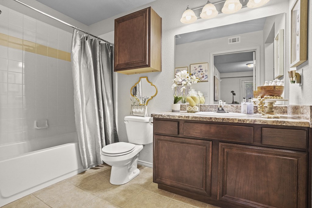 A bathroom with a white toilet and a wooden cabinet.