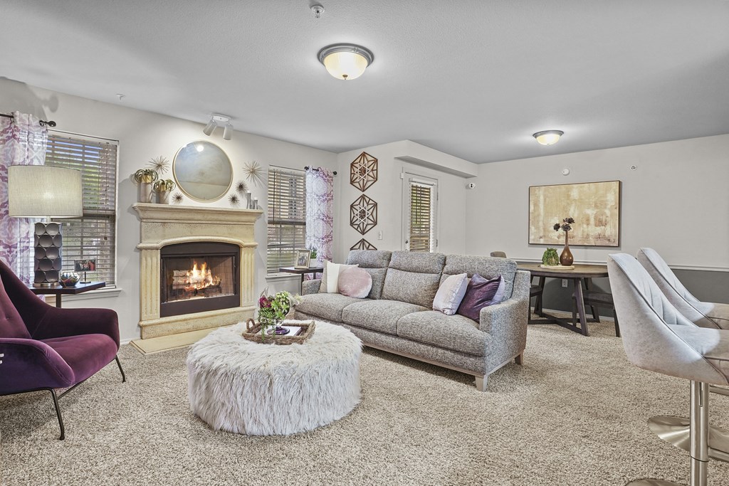 A living room with a fireplace and a grey couch.