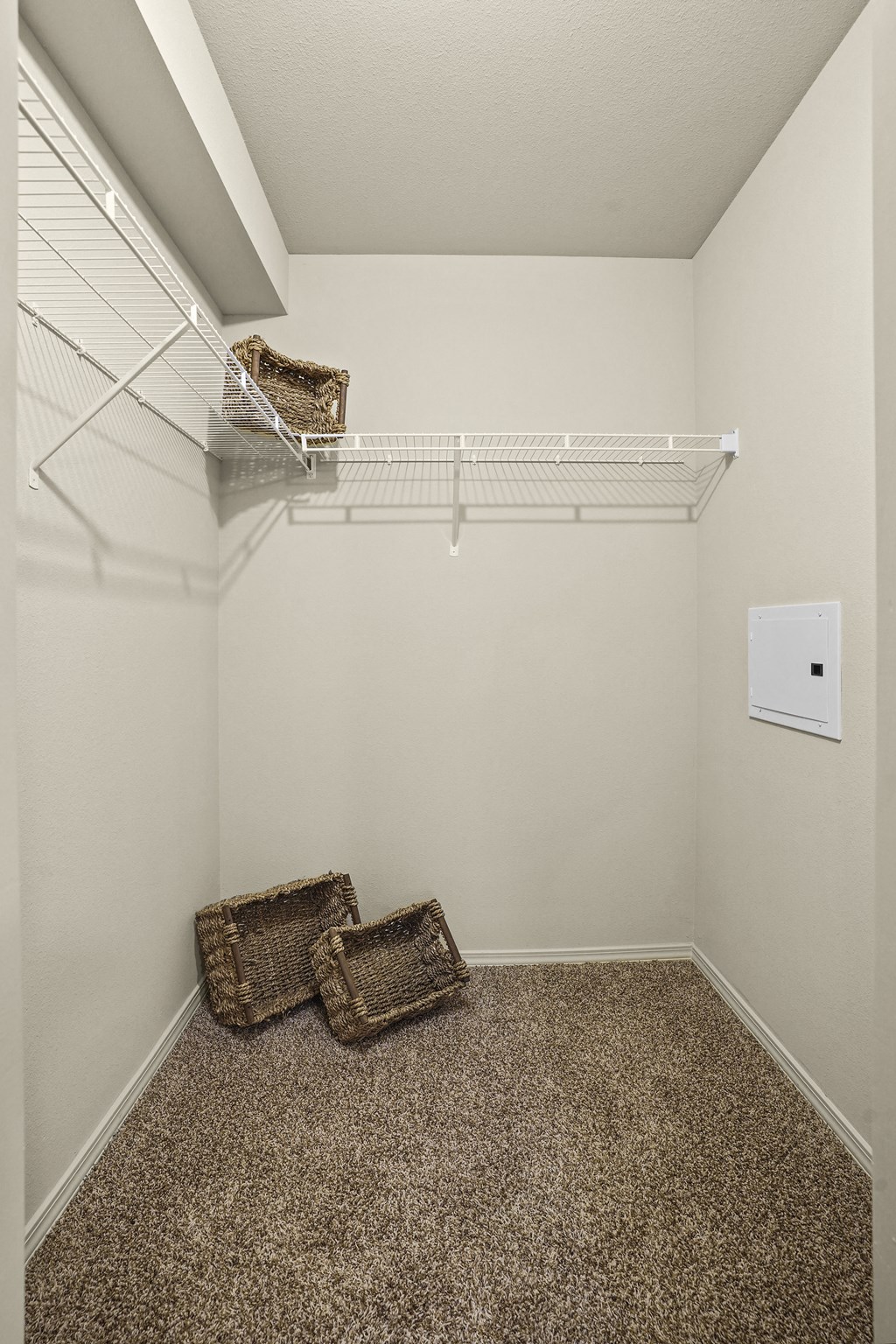A small room with a wire shelf and two baskets on the floor.