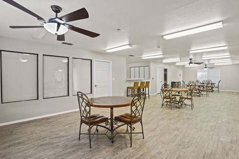 A room with a table and chairs and a ceiling fan.