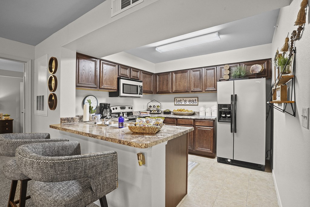 A kitchen with a marble countertop and a white refrigerator.