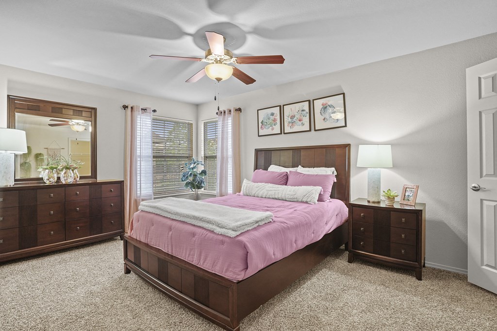 A bedroom with a bed, dresser, and ceiling fan.