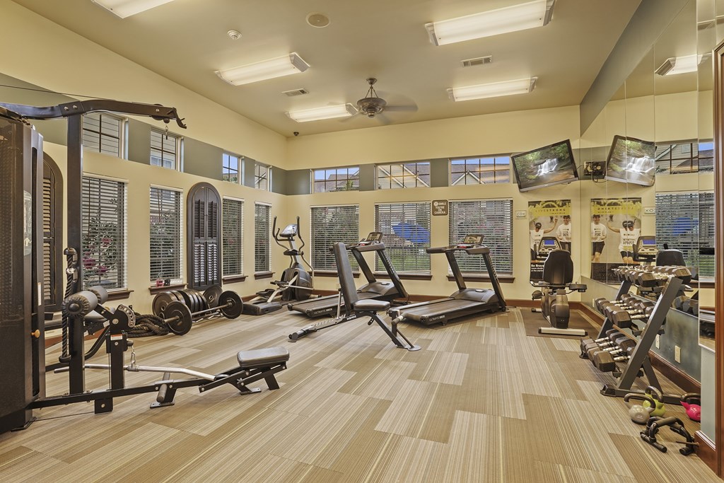 A spacious gym with a variety of equipment and a large mirror on the wall.