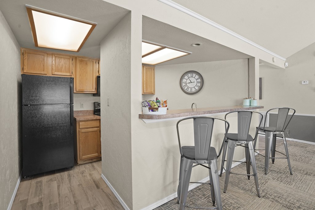 A kitchen with a black fridge and bar stools.