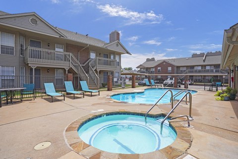 A swimming pool surrounded by chairs and a building in the background.