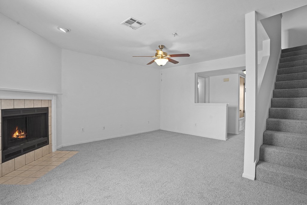 A living room with a fireplace and a staircase.
