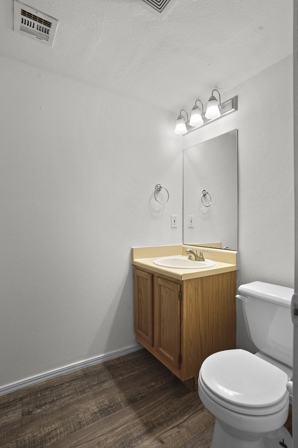 A bathroom with a toilet, sink, and mirror.