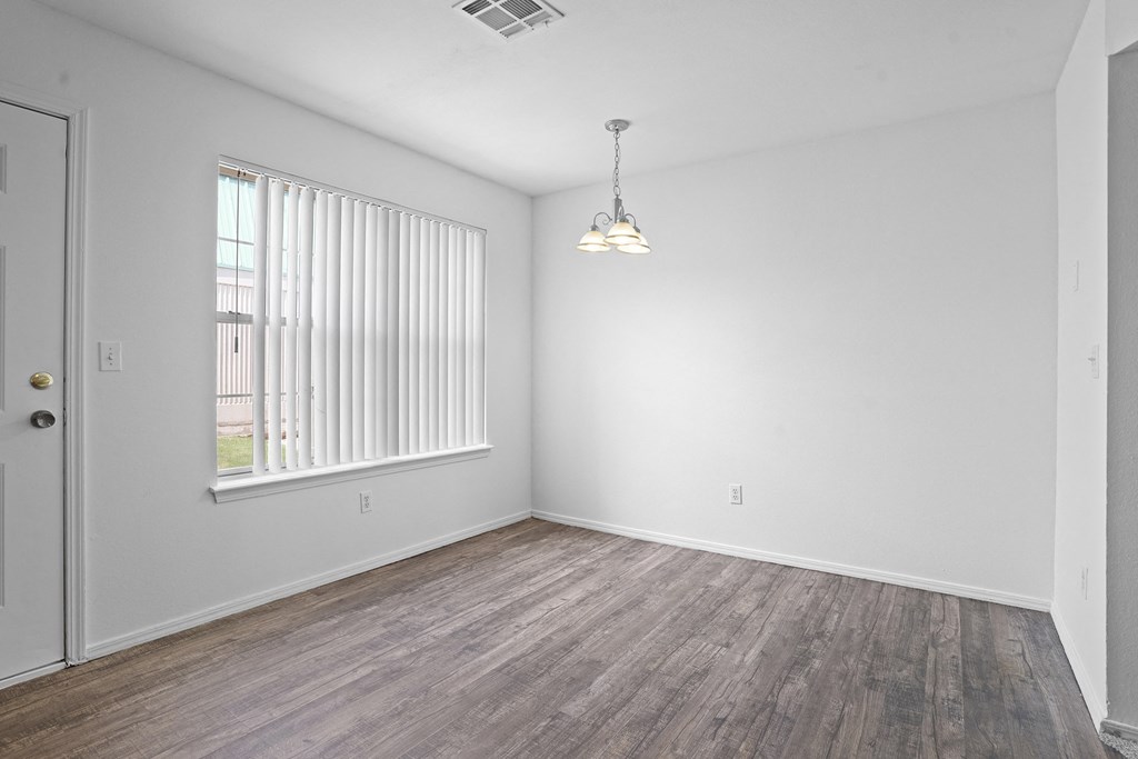 A room with wooden flooring and a window with blinds.