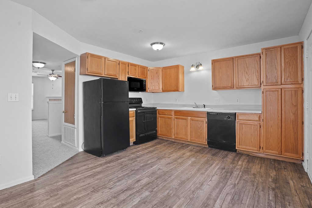 A kitchen with wooden cabinets and black appliances.