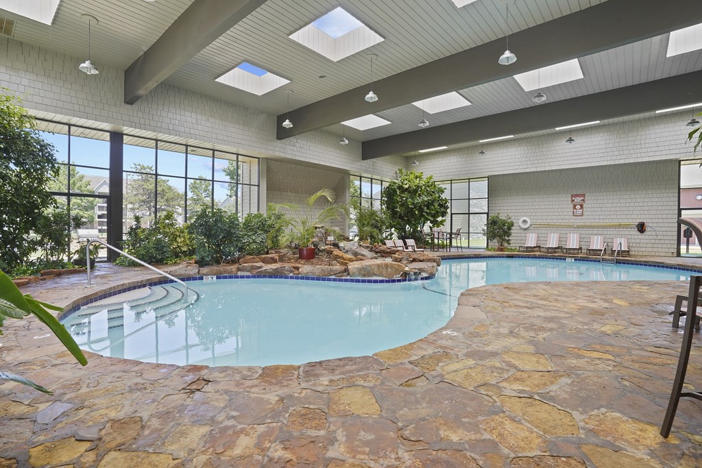 A swimming pool in a room with stone flooring and ceiling.