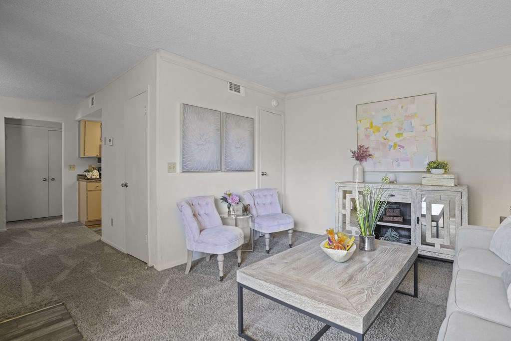 A living room with a grey coffee table and two white chairs.