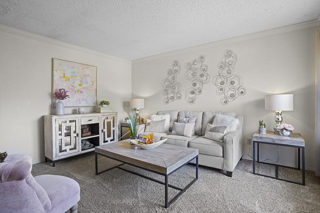 A living room with a white couch, a grey armchair, a coffee table, and a painting on the wall.