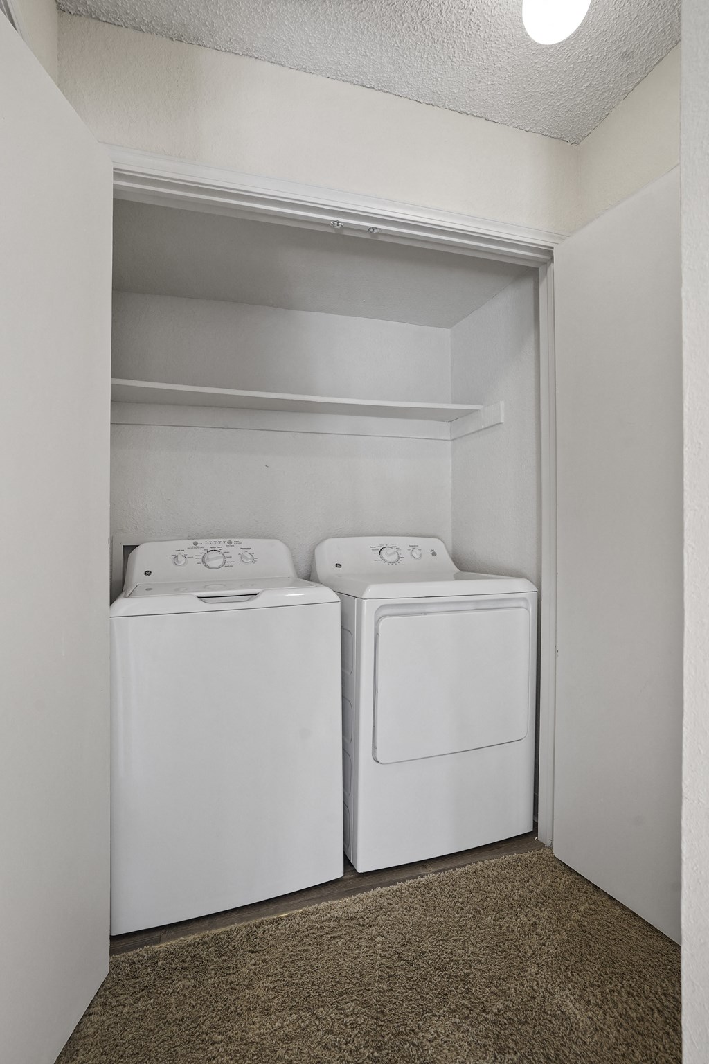 Two white washing machines in a small laundry room.
