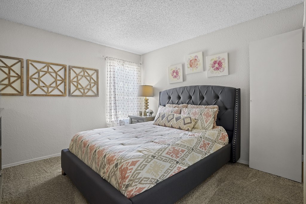A bedroom with a large bed and a window with curtains.