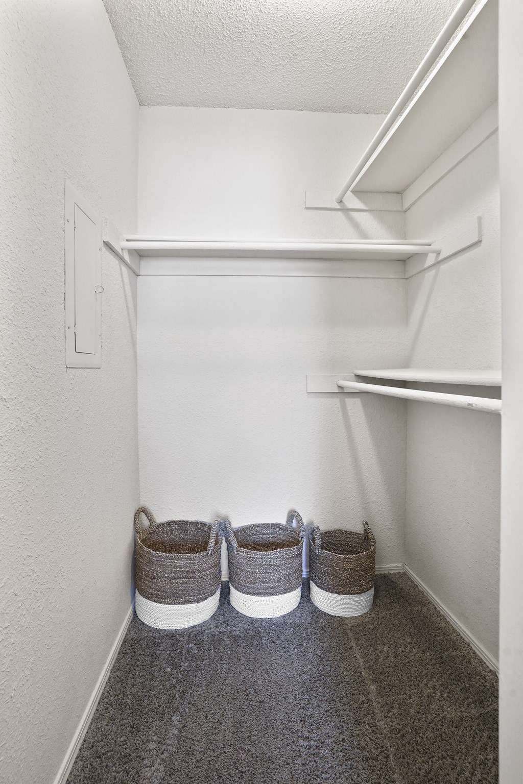 Three baskets are placed on the floor of a white hallway.