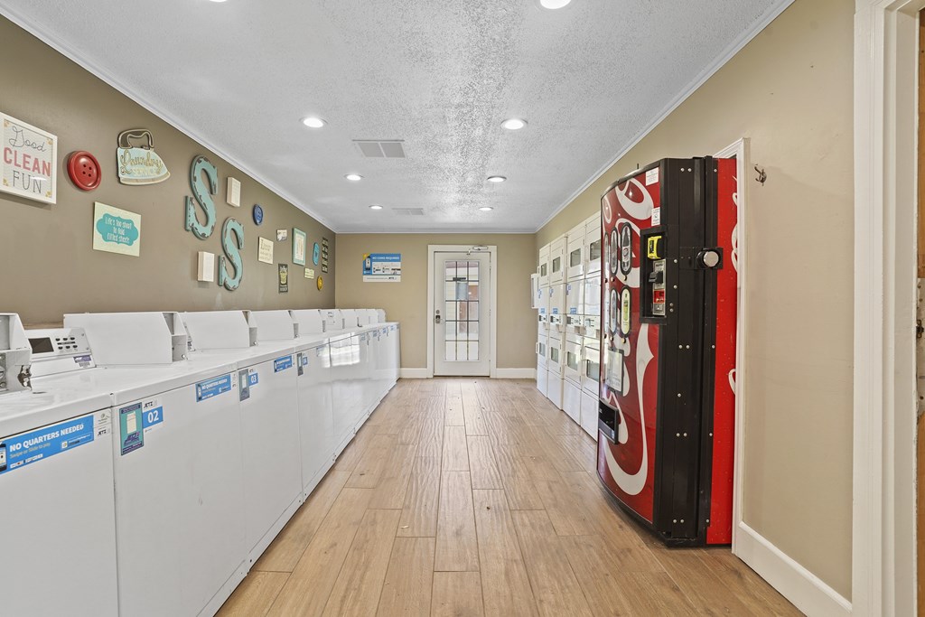 A laundry room with washers and dryers lined up.