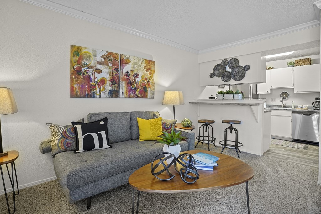 A living room with a grey couch and a painting on the wall.
