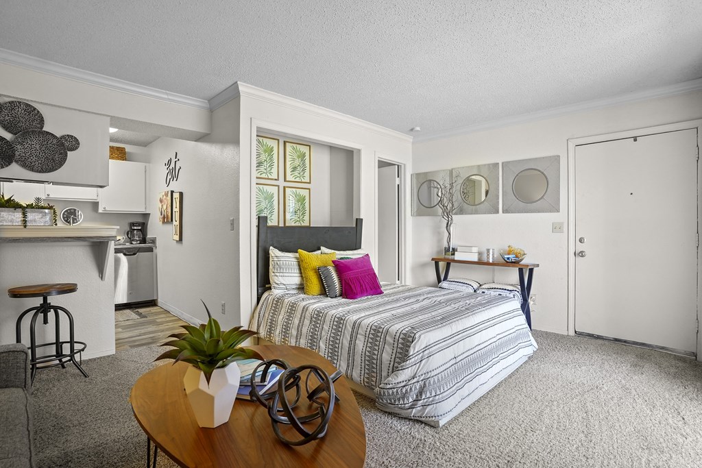 A bedroom with a bed, a table, and a bar area.