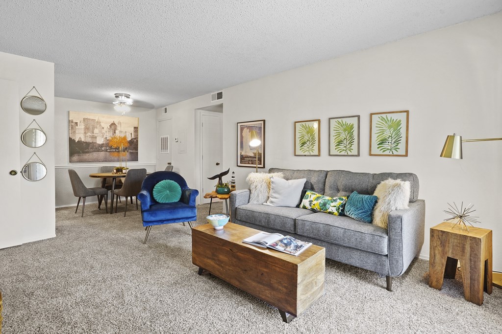 A living room with a grey couch, a blue chair, and a wooden coffee table.