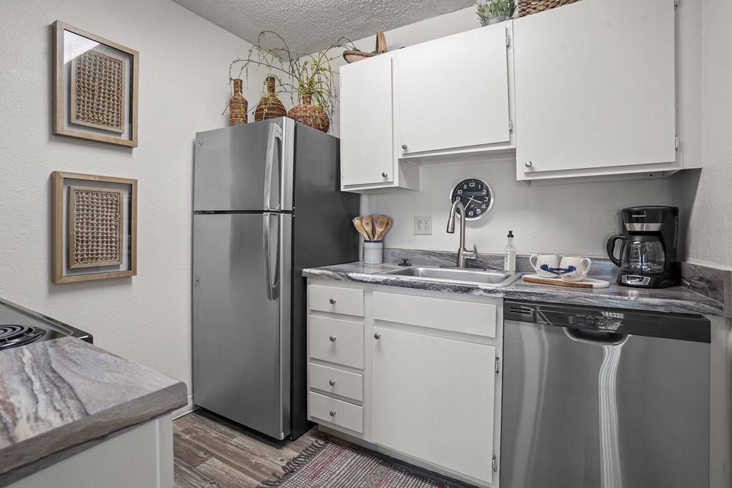 A kitchen with a refrigerator, sink, and dishwasher.