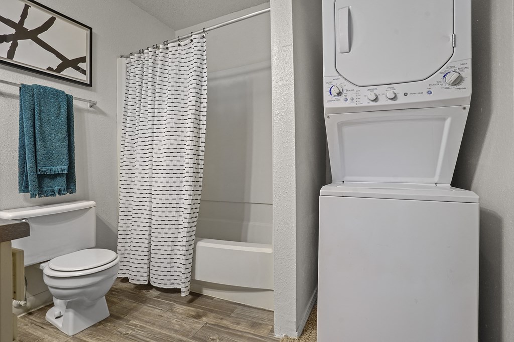 A white toilet sits next to a white washing machine in a bathroom.