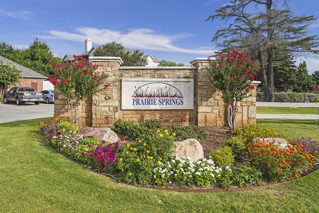 A sign that says "Prairie Springs" is surrounded by flowers.
