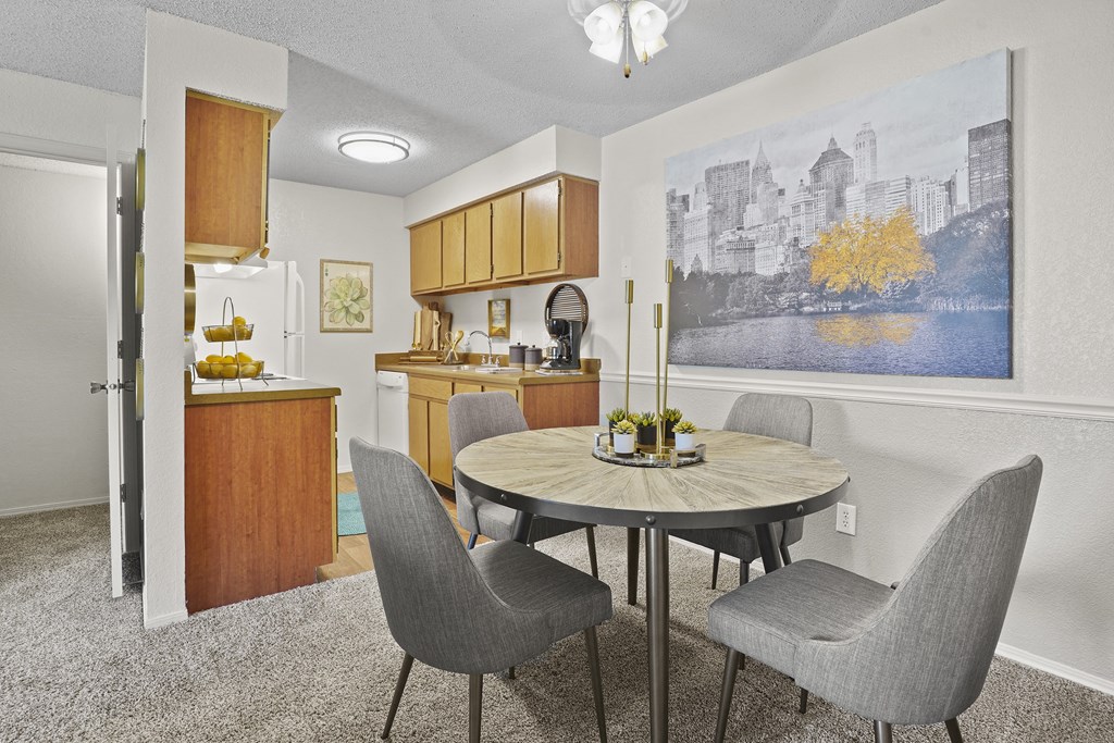 A kitchen with a table and chairs in front of a framed picture of a cityscape.