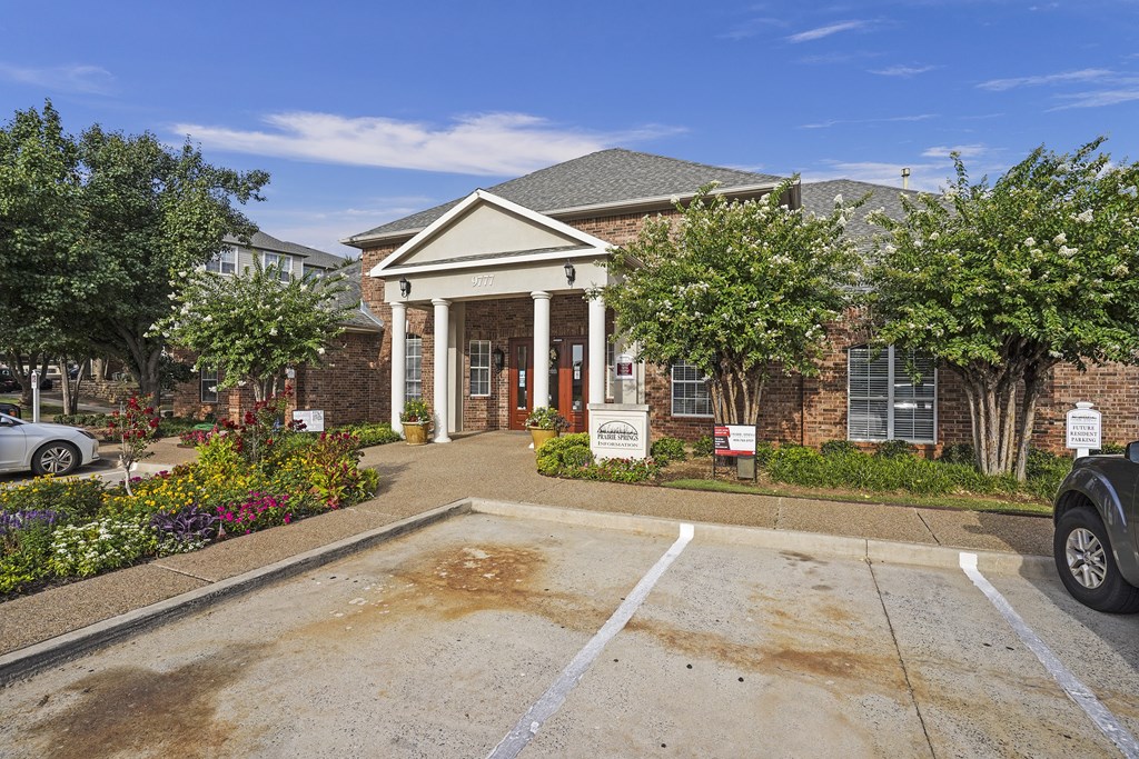 A building with a white columned entrance and a parking lot in front.