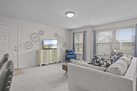 A living room with a grey couch, a wooden cabinet, and a flat screen TV.