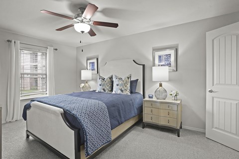A bedroom with a bed, nightstand, and a ceiling fan.