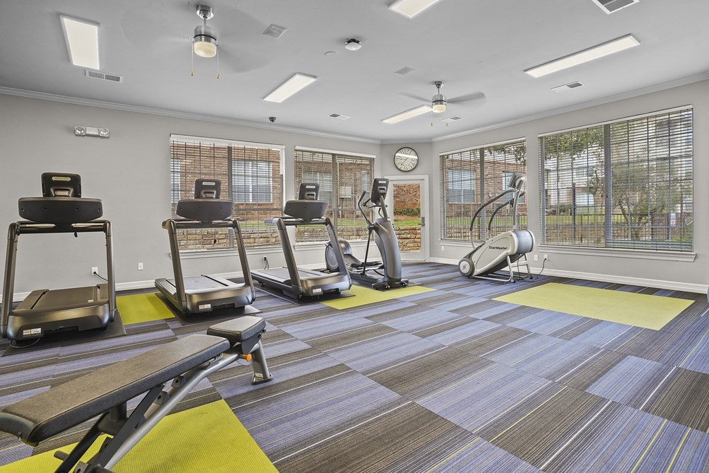 A gym with treadmills, elliptical machines, and a fan.
