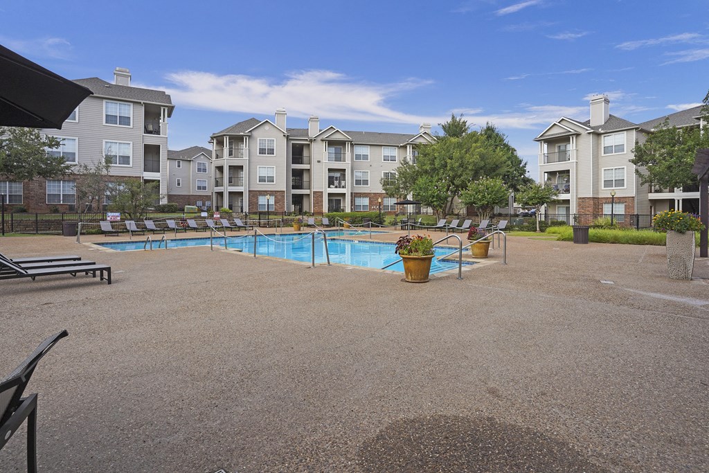 A pool area with a blue pool and a brown ground.