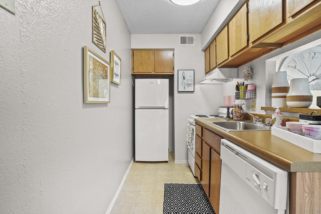 A kitchen with a white dishwasher and a white refrigerator.