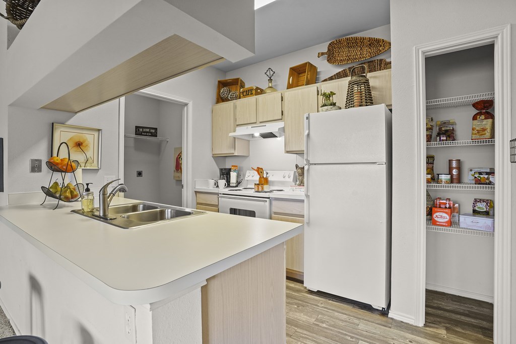 A kitchen with a white fridge and a white sink.