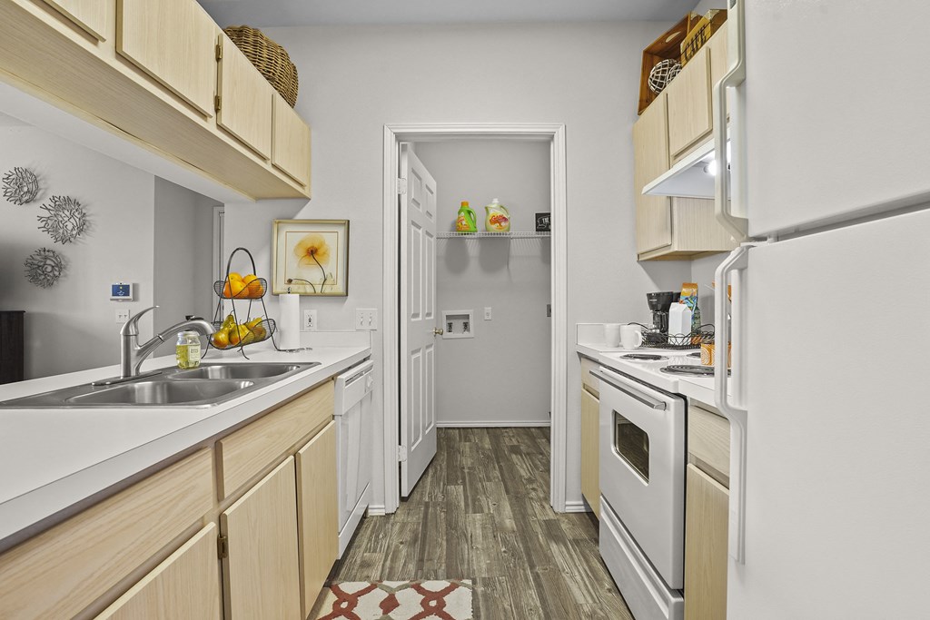 A kitchen with a white fridge, sink, and wooden cabinets.