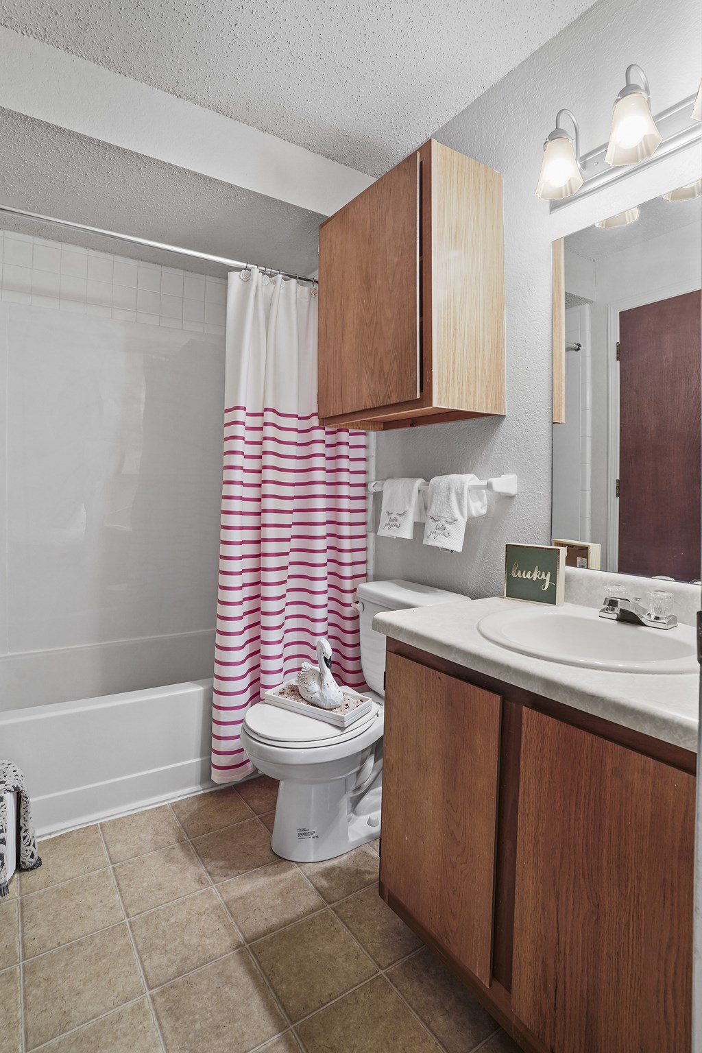 A white toilet sits in a bathroom with a pink shower curtain.