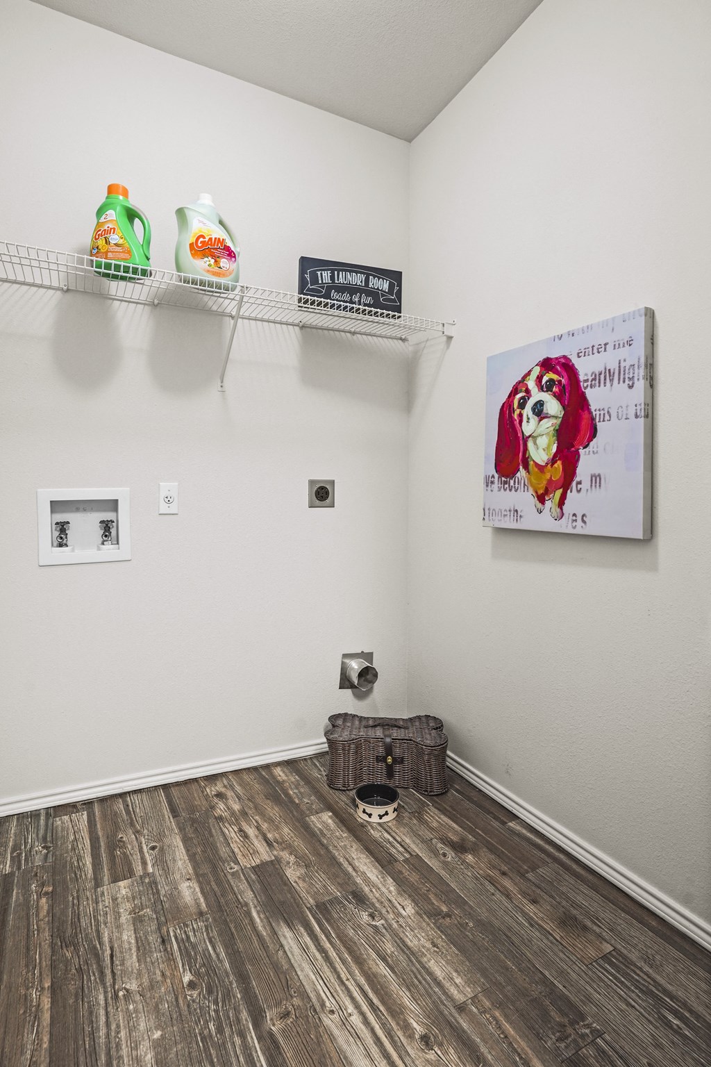 A room with a wooden floor and a picture of a dog on the wall.