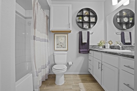 A white toilet in a bathroom with a purple towel hanging on the wall.