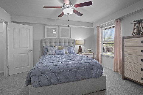 A bedroom with a large bed and a ceiling fan.